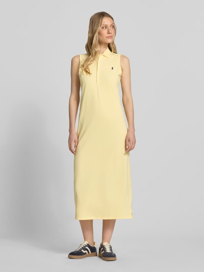 Modelka kobieca ma na sobie jednokolorowe, żółte Figurinumspielendes Polokleid aus Baumwoll-Mix von Polo Ralph Lauren z prostym dołem, bez rękawów, z kołnierzem polo, krótką listwą guzikową, bocznym rozcięciem, logo, materiał bawełniany w fakturze piké, długość midi, widok całej sylwetki z przodu.