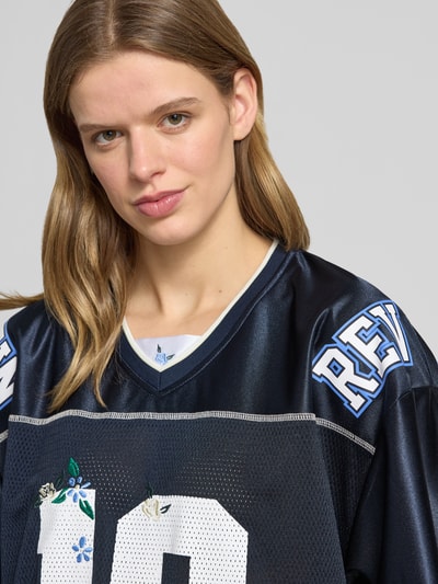 Frauenmodel trägt T-Shirt mit V-Ausschnitt von Review, semitransparenter Look, 1/2-Arm, Dunkelblau und Weiß, Nahaufnahme Oberkörper.