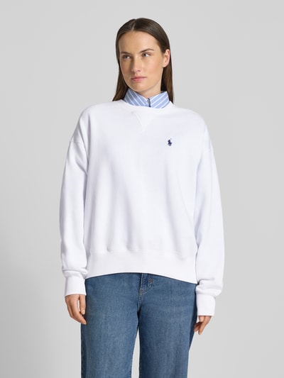 Vrouwenmodel draagt Oversized Sweatshirt aus Baumwoll-Mix van Polo Ralph Lauren in effen wit met logo-detail en ronde hals, sweatmateriaal, geribde boorden, oversized fit, voorkant borsthoogte, close-up shot.