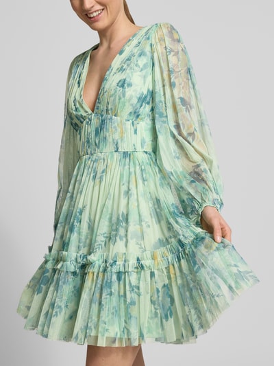 Vrouwenmodel draagt Cocktailkleid aus Tüll mit V-Ausschnitt van LACE & BEADS, lichtgroene tinten, bloemmotief, a-lijn, minijurk van tule, diepe V-hals, lange mouw, ruglengte 90 cm, borstwijdte 33 cm, mouwlengte 61 cm, detailopname bovenlichaam.