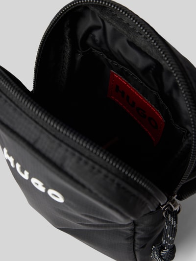 Produktfoto, Umhängetasche mit Logo-Detail und Mini Pouch von BOSS, schwarze unifarbene Textilstruktur, sichtbares Markenetikett innen.