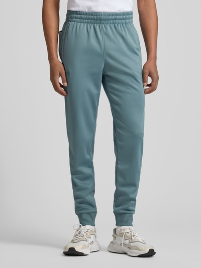 Męski model nosi Sweatpants mit elastischem Bund od Under Armour, luźny krój, elastyczny pas, kieszenie, widok z przodu, cała sylwetka.