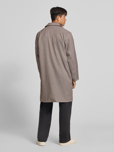 Männermodel trägt Trenchcoat mit Knopfleiste und Label-Patch von ANOTHER COTTON LAB, braun gemustert, gerader Schnitt, Ganzkörperansicht Rückansicht.