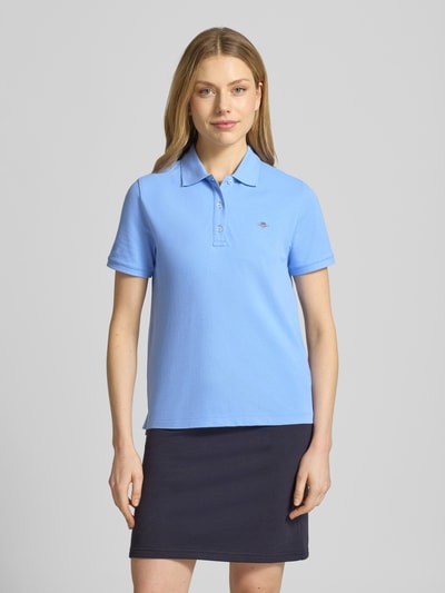 Frauenmodel trägt Poloshirt mit Logo-Stitching und Polokragen von Gant in Blau, Reine Baumwolle, Regular-Fit, kurze Knopfleiste, Ganzkörperansicht von vorne. Rückenlänge bei Größe S: 57 cm.