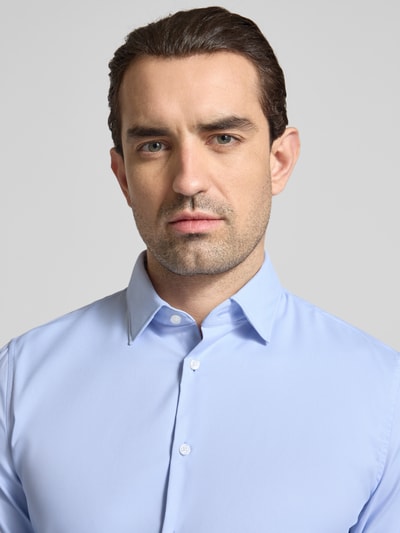 Męski model nosi Slim Fit Business-Hemd mit Kentkragen und extra langem Ärmel od Jake*s, materiał z domieszką stretchu, jasnoniebieski, krój slim fit, koszula, widok z przodu, zbliżenie na górną część ciała, długość pleców w rozmiarze 39/40: 80 cm, szerokość w rozmiarze 39/40: 44 cm, długość rękawa w rozmiarze 39/40: 71 cm.