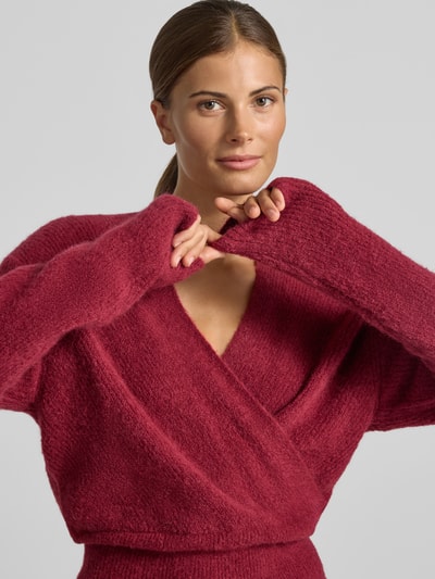 Frauenmodel trägt Strickpullover in Wickel-Optik Modell 'Bondie Hope' von MSCH Copenhagen in Rot, grobe Textur, Mix mit Woll-Anteil, Nahaufnahme Oberkörper.