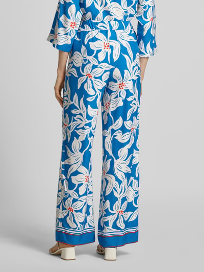 Vrouwenmodel draagt stoffen broek van zuiver viscose model 'Rylie' van GUIDO MARIA KRETSCHMER WOMAN, relaxed fit, all-over look, elastische band, maat 36 bandwijdte 36 cm, binnenbeenlengte 77 cm, blauw met witte bloemen, rechte pijpen, geheel lichaamsaanzicht achterkant