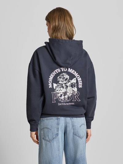 Kobiece modelka nosi Oversized Hoodie mit Label-Stitching Modell 'MARIALVA' od Pegador, bawełniany miks, kangurowa kieszeń, granatowy kolor, nadruk z tyłu, widok całej sylwetki z tyłu.