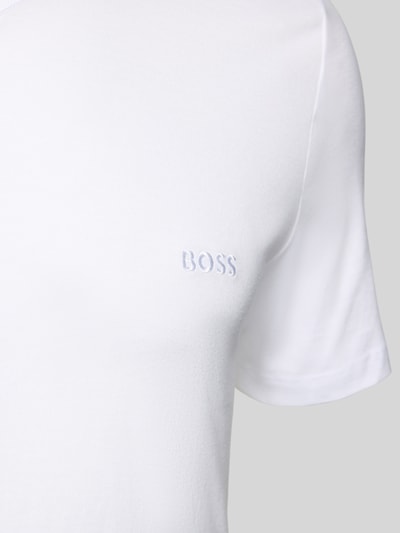 Männermodel trägt T-Shirt mit V-Ausschnitt im 3er-Pack Modell 'Classic' von BOSS aus weißer reiner Baumwolle mit Label-Stitching, Nahaufnahme Oberkörper.