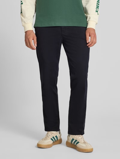 Męski model nosi Straight Fit Chino mit Eingrifftaschen Modell 'Vance' od Jack & Jones, granatowe, bawełniany, elastyczny materiał, krój straight fit, kieszenie boczne i tylne, zapięcie na guzik i zamek, szerokość w rozmiarze 32/32: 43 cm, długość nogawki od wewnątrz: 67 cm, widok z przodu na całe ciało.