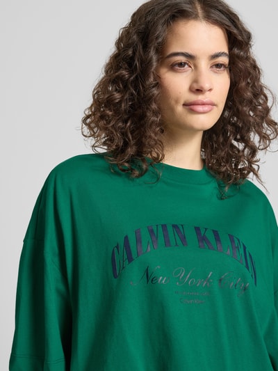 Frauenmodel trägt Cropped T-Shirt mit Logo-Print von Calvin Klein Jeans in Grün, reine Baumwolle, Rundhalsausschnitt, Nahaufnahme Oberkörper.