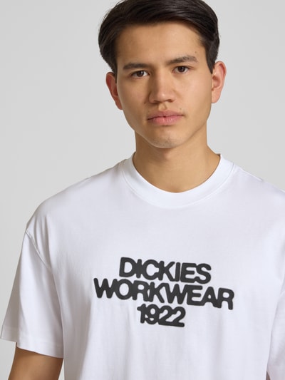 Männermodel trägt T-Shirt mit Label-Print Modell 'TORREY' von Dickies, weiße Reine Baumwolle, Regular-Fit, Rundhalsausschnitt, Nahaufnahme Oberkörper.