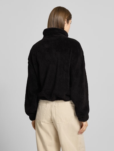 Frauenmodel trägt Loose Fit Fleecejacke mit Stehkragen Modell 'ANNA CONTACT' von Only aus schwarzem Kunstwebfell, Ganzkörperansicht Rückansicht.