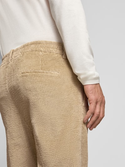 Männermodel trägt Straight Fit Hose aus Baumwoll-Mix Modell 'Chasy' von DRYKORN in beigefarbener Cord-Optik, Nahaufnahme Rückansicht. Elastischer Stoff, Gesäßtaschen, Knopf- und Reißverschluss, Bundweite 40 cm, Innenbeinlänge 71 cm.