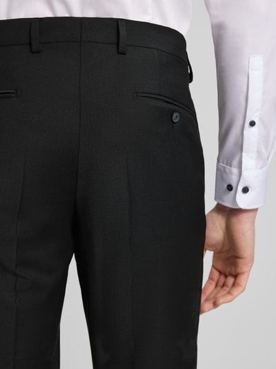 Männermodel trägt Slim Fit Anzug mit 2-Knopf-Sakko Modell 'Grant' von Pierre Cardin, schwarze glatte Textur, Nahaufnahme Rückansicht. Material-Mix mit Schurwoll-Anteil, Anzughose mit Bügelfalten, typische Details wie Pattentaschen und Reverskragen, hochwertig verarbeitet.