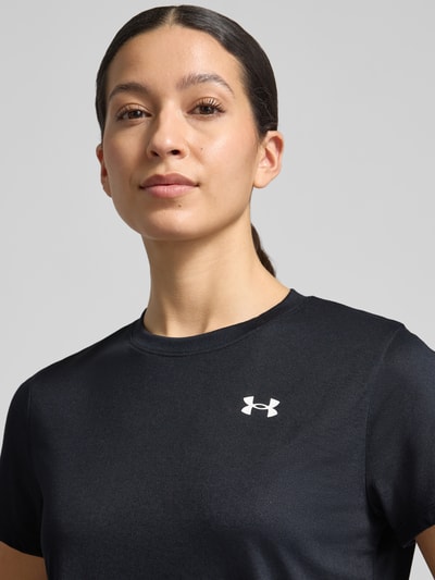 Vrouwenmodel draagt Funktionsshirt mit Rundhalsausschnitt und Logo van Under Armour, regular fit, zwart, logo op de borst, ronde hals, ruglengte bij maat S: 61 cm, close-up bovenlichaam vooraanzicht.