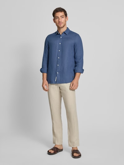 Männermodel trägt Regular Fit Leinenhemd aus reinem Leinen Modell 'CORE' von Scotch & Soda in Blau, Kentkragen, Durchgehende Knopfleiste, Label-Stitching, Langärmelig, Rückenlänge 78 cm, Schulterbreite 45 cm, Ärmellänge 66 cm, Ganzkörperansicht von vorne.