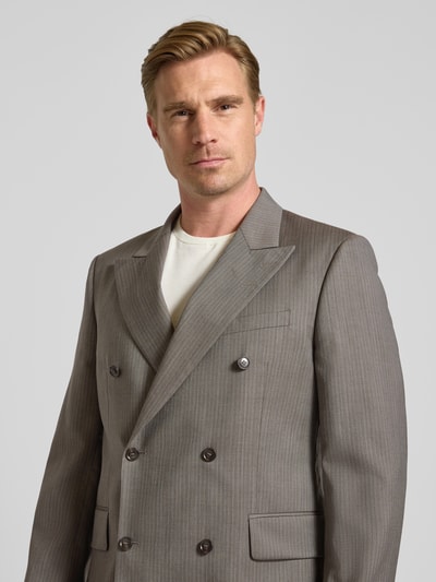 Mannelijk model draagt Sakko aus Wolle mit Label-Patch und Pattentaschen van Tiger of Sweden in lichtgrijs met fijne strepen, regular fit, reverskraag, met dubbele rij knopen, paspelzak op de borst en zijstrookzakken, detailopname bovenlijf. Ruglengte maat 50: 78 cm, schouderbreedte: 50 cm, mouwlengte: 68 cm.