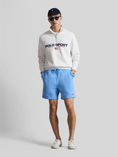 Mężczyzna model nosi Regular Fit Sweatshorts aus Baumwoll-Mix od Polo Ralph Lauren, jasnoniebieski, bawełniany dres, krój regular fit, jednolity kolor, haftowany napis z logo, elastyczny pas z troczkiem, kieszenie boczne i tylna, widok całej sylwetki z przodu.