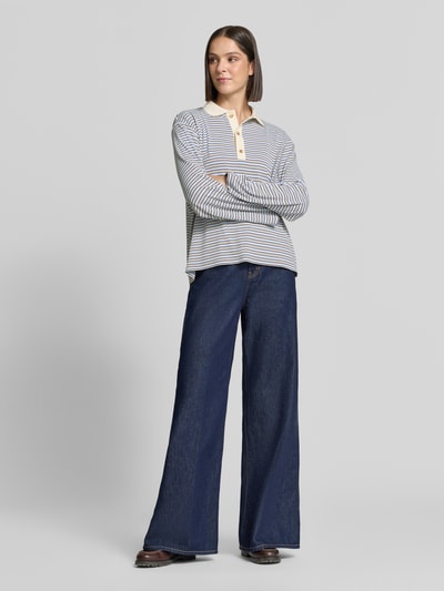 Frauenmodel trägt Relaxed Fit Poloshirt in langärmeligem Design von Neo Noir, in Streifenoptik, weiches Material, Ganzkörperansicht von vorne. Damen Poloshirt, Elastischer Material-Mix, Polokragen, Rückenlänge bei Größe 36: 62 cm.
