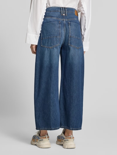 Frauenmodel trägt Wide Fit Jeans mit Baumwoll-Anteil Modell 'Derive' von DRYKORN in Dunkelblau, mit aufgesetzten Taschen und Struktur, Ganzkörperansicht Rückansicht. Damen Jeans, Material-Mix, Knopf- und Reißverschluss, Bundweite 40 cm, Innenbeinlänge 67 cm.