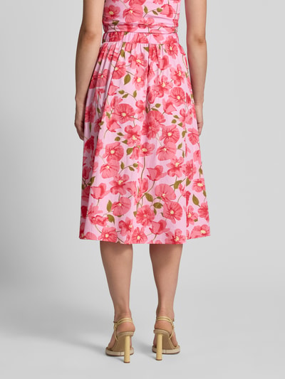 Frauenmodel trägt Midirock im Allover-Look Modell 'CASTLE' von MANGO, Baumwolle, rosa-rote Blüten, elastischer Bund, Ganzkörperansicht Rückansicht.