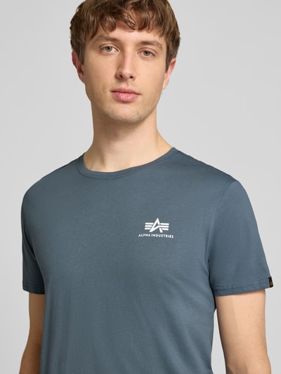 Mężczyzna nosi t-shirt z bawełny, prosty krój, okrągły dekolt, Model 'BASIC' od Alpha Industries, detale z logo, długość tyłu 67 cm, zbliżenie na górną część ciała