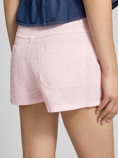 Vrouwenmodel draagt Leinenshorts mit Bindegürtel und Eingrifftaschen van Gina Tricot in lichtroze, mix van katoen en linnen, loose fit, met strikceintuur, zij-steekzakken en achterzakken, detailopname rugaanzicht.