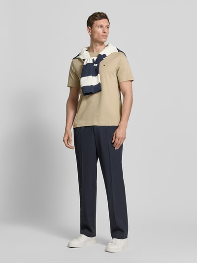 Mannelijk model draagt Regular Fit T-Shirt uit zuiver katoen van Tommy Hilfiger, effen, logo-detail, ronde hals, korte mouw, interlock, Ganzkörperansicht von vorne.