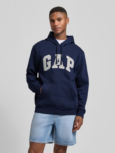 Männermodel trägt Hoodie mit Logo und Känguru-Tasche von GAP in Dunkelblau, Baumwoll-Mix, Regular Fit, Nahaufnahme Oberkörper.