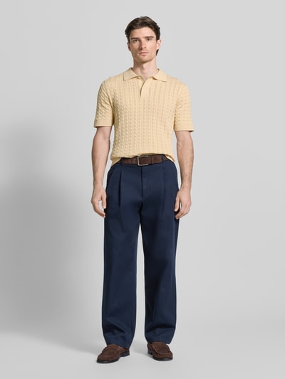 Męski model nosi Regular Fit Poloshirt aus reiner Baumwolle Modell 'MATTIS' od SELECTED HOMME w żółtym kolorze, struktura dzianiny z wzorem warkoczowym, krótki rękaw, gładki kołnierz polo, żebrowane wykończenia, całkowity widok z przodu.