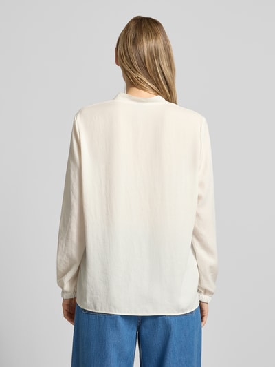 Frauenmodel trägt Bluse mit V-Ausschnitt und Label-Detail von Marc Cain in Creme, locker geschnitten, elastische Ärmelabschlüsse, Ganzkörperansicht Rückansicht.