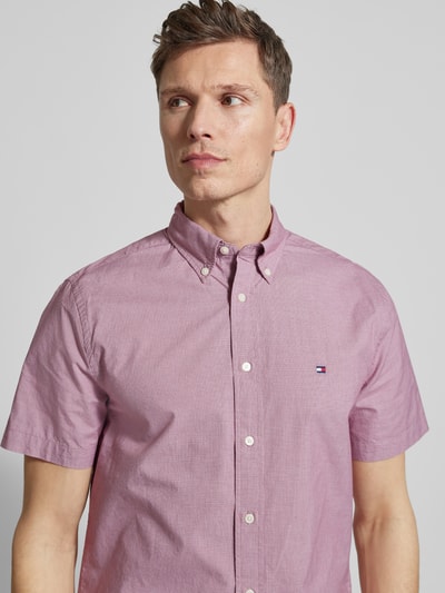 Mannenmodel draagt 'Regular Fit Freizeithemd aus reiner Baumwolle' van Tommy Hilfiger in lichtroze met mini-hanentandmotief, lichte knopen, korte mouwen, button-down kraag, logo-stiksel links op de borst, popeline structuur, puur katoen. Nahaufnahme bovenlichaam.