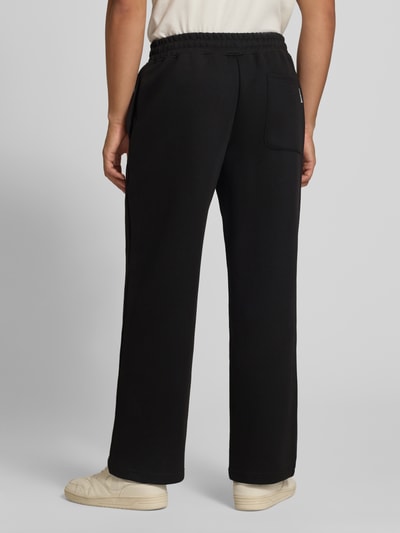 Männermodel trägt Straight Fit Sweatpants mit elastischem Bund von JACK & JONES in Schwarz, glatte Struktur, Ganzkörperansicht Rückansicht. Material-Mix mit Baumwoll-Anteil, Eingrifftaschen, Innenbeinlänge bei Größe M 76 cm.
