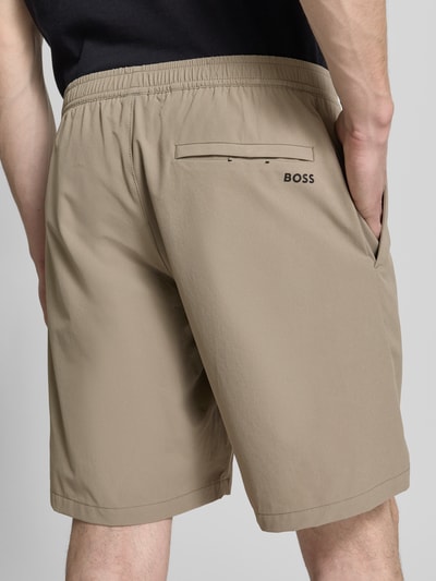 Männermodel trägt Regular Fit Sport-Shorts mit Label-Print Modell 'TREVOL' von BOSS Green aus 4-Wege-Stretch, Ganzkörperansicht Rückansicht.
