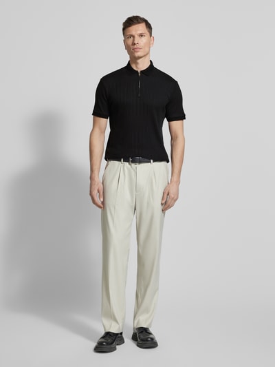 Męski model nosi Regular Fit Poloshirt mit Bio-Baumwoll-Anteil Modell 'FAVE' von SELECTED HOMME, czarny, krój regular fit, polokragen, krótki zamek, krótki rękaw, ściągacze, prążkowana struktura, unikatowa faktura, jednolity kolor, całopostaciowy widok z przodu.