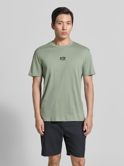 Mannenmodel draagt T-shirt met logo en ronde hals van ARMANI EXCHANGE, puur katoen, regular fit, ruglengte maat M 82 cm, geheelaanzicht voorkant.