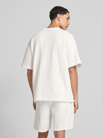 Männermodel trägt Oversized T-Shirt mit Strukturmuster von Pegador aus Baumwoll-Mix mit Rundhalsausschnitt, Oversized-Fit, Logo-Stitching, Rückenlänge bei Größe M 71 cm, Ganzkörperansicht Rückansicht.