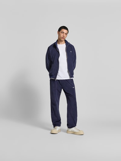 Männermodel trägt Oversized Sweatjacke aus Baumwolle von RHUDE in Dunkelblau mit Frottee-Struktur, Zweiwege-Reißverschluss, elastische Abschlüsse, Ganzkörperansicht von vorne. Rückenlänge Größe M: 68 cm, Schulterbreite: 48 cm, Ärmellänge: 68 cm.