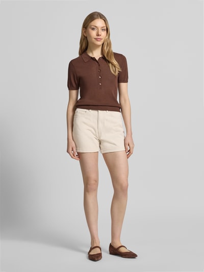 Vrouwenmodel draagt Loose Fit Jeansshorts uit katoenmix model 'ZURI' van Vero Moda in denimlook met labelpatch, 5-pocketmodel, twillstructuur, kleur beige, knoop- en ritssluiting, vaste omslag, vooraanzicht hele lichaam.