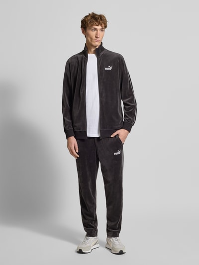 Männermodel trägt Sweatjacke aus Velours mit Label-Stitching von PUMA PERFORMANCE in Dunkelgrau, Regular Fit, Ganzkörperansicht von vorne.