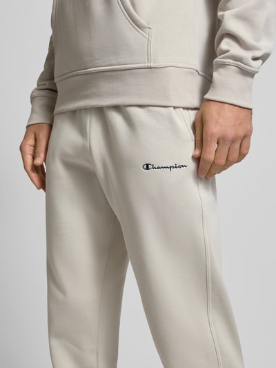 Mężczyzna nosi Straight Fit Sweatpants mit Label-Stitching od CHAMPION z mieszanki bawełny, elastyczny pas, wyhaftowane logo, zbliżenie na biodra.