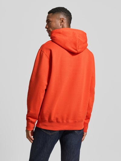 Männermodel trägt Hoodie mit Logo-Print und Känguru-Tasche van Wood Wood in fel oranje, katoen, loose fit, rugaanzicht, context volgens beschrijving