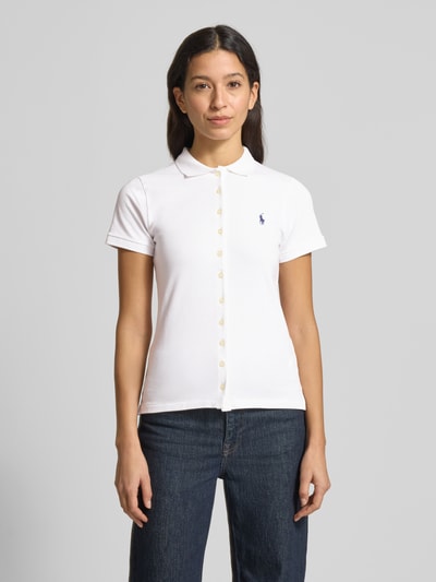 Frauenmodel trägt Poloshirt mit Knopfleiste von Polo Ralph Lauren aus Baumwoll-Elasthan-Mix, Slim Fit, Hemdblusenkragen, Label-Stitching, Rückenlänge bei Größe S 55 cm, weiße Farbe, glatte Textur, Ganzkörperansicht von vorne.