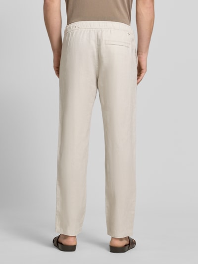 Männermodel trägt Leinenhose mit Eingrifftaschen Modell 'JABARI' von Samsøe Samsøe in Beige, Relaxed-Fit, Gesäßleistentasche, Ganzkörperansicht Rückansicht.