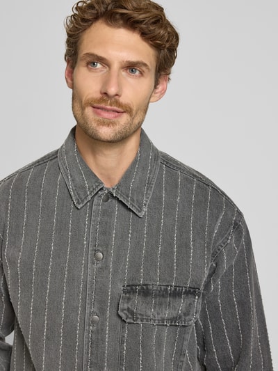 Männermodel trägt Regular Fit Hemdjacke aus reiner Baumwolle Modell 'David' von Wood Wood, Denim-Optik, Nahaufnahme Oberkörper.