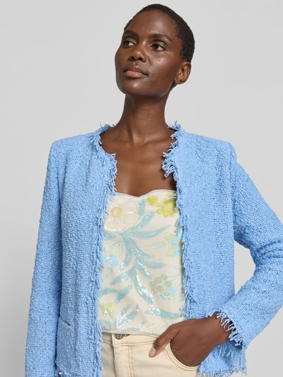 Frauenmodel trägt Jacke mit Baumwoll-Anteil im Bouclé-Look von IRO in Hellblau, Material-Mix mit Leistentaschen, Ganzkörperansicht von vorne. Slim-Fit, offene Vorderseite, Rückenlänge bei Größe 36: 53 cm, Brustweite: 40 cm, Ärmellänge: 61 cm.