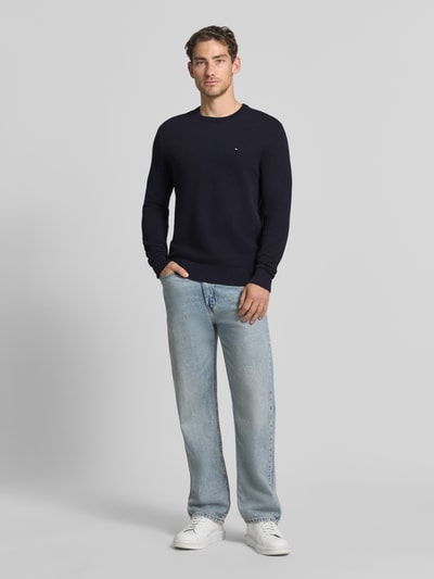 Männermodel trägt Regular Fit Pullover aus reiner Baumwolle von Tommy Hilfiger in Dunkelblau zu Jeans, Ganzkörperansicht von vorne. Herren Pullover von Tommy Hilfiger.
