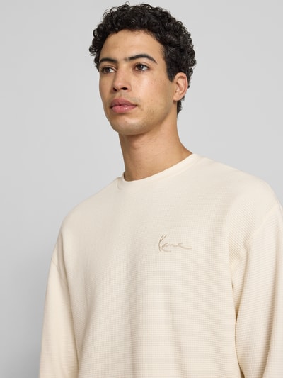 Männermodel trägt Regular Fit Sweatshirt mit Strukturmuster von KARL KANI in Beige, reine Baumwolle, Logo-Stitching, Nahaufnahme Oberkörper.
