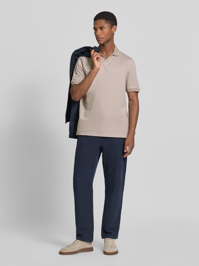 Männermodel trägt Regular Fit Poloshirt aus Baumwolle mit V-Ausschnitt von MAERZ Muenchen, beige, Label-Detail, Ganzkörperansicht von vorne. Rückenlänge bei Größe 50: 71 cm.